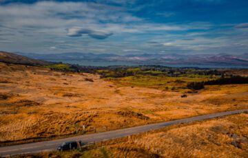 Weite irische Landschaft mit Bergen, See und Landstraße in County Kerry
