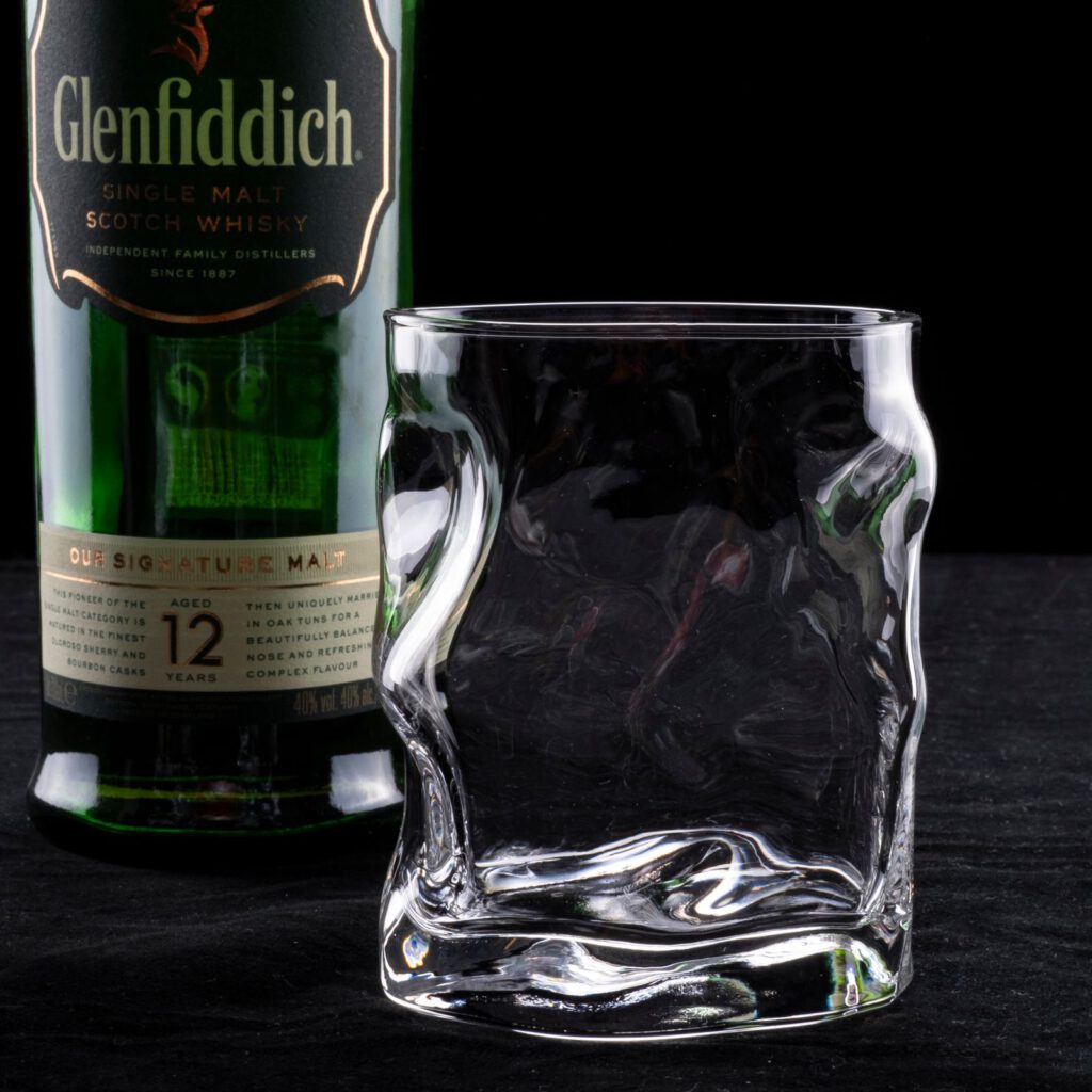 Whiskyglas und Flasche vor dunklem Hintergrund als Symbol schottischer Brennkunst
